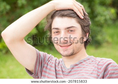 A young male model is looking into the camera attractively while brushing back his hair