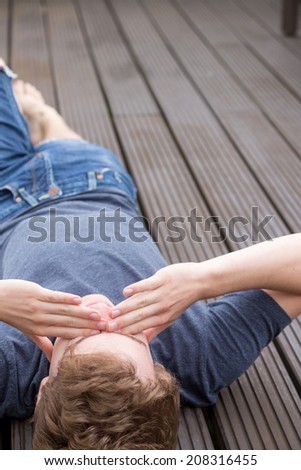 A young blonde male model is lying on the ground and needs to think