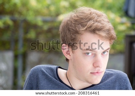 A young blonde male model is looking straight at the camera and looking down and to the right. He is mad at you.