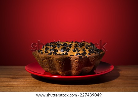 Moms home made chocolate cake in a red plate on a wooden flloor.