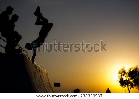 Roller skater handstands in skate at sunset time. Two of friends watching him. At Bostanli Izmir Turkey May 23 2014