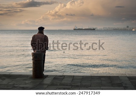 Old man watching the sea and ships in the evening. Izmir, Turkey - January 28, 2015
