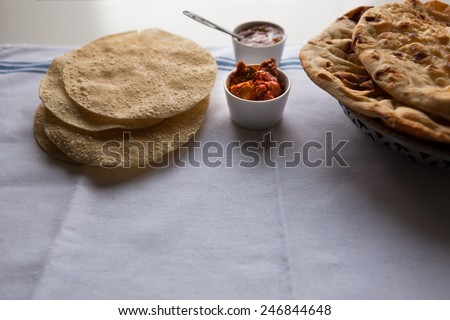 Fresh Indian flat breads nan and poppadom served with mango chutney and pickle on the table