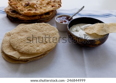 Indian flat breads poppadom and nan with mango chutney and dip sauce on the table