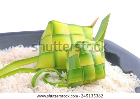 Ketupats, a natural rice casing made from young coconut leaves for cooking rice on rice grain and black glass plate