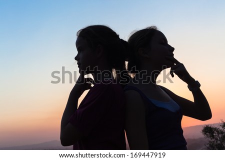Friends Girls Decisions Girl friends teenagers decisions back to back in late afternoon sunset silhouetted