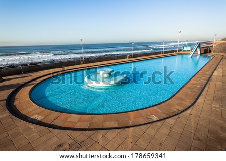 Swimming Pool Holidays Beach Swimming pool fountain slide and shallow water for children playtime with  family next to ocean beach out of season nobody