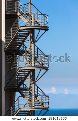 Ocean Building Fire Escape Stairs  Building back fire escape metal stairs section overlooking blue ocean.