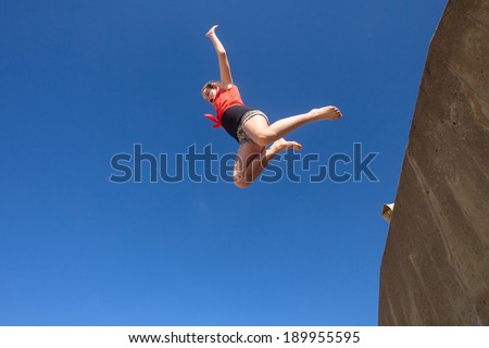 Girl Jumping Blue Sky Parkour Teen girl jumping off wall against blue sky onto beach in parkour