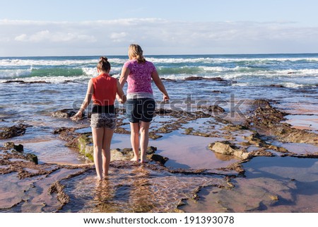 Mother Daughter Explore Beach Rock Pools Mother daughter girls on ocean beach low tide rock reefs exploring marine life