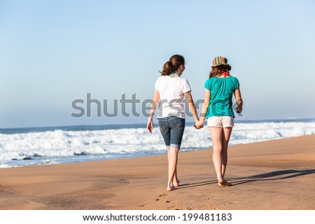 Teen Girls Talk Fun Time Beach Waves Teen girls walking together social talk fun laugh time hanging out at beach with ocean waves.