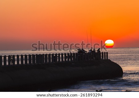 Fishing Sunrise Ocean\
Fishermen fishing dawn on pier jetty as sun rises on the ocean horizon.