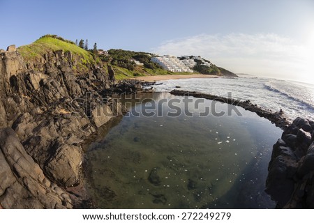 Tidal Pool Rocky Coastline\
Small Beach coastline rocky cove tidal pool for swimming surfing ocean waves with  apartment houses on the landscape