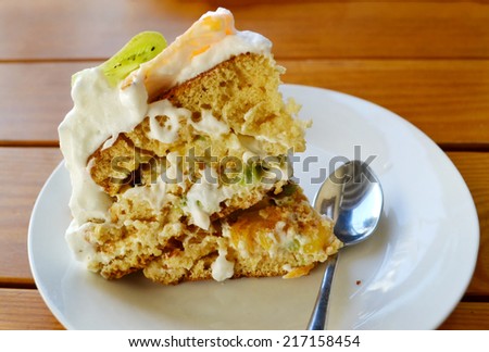 Slice of fruit cake with cream, kiwi and orange