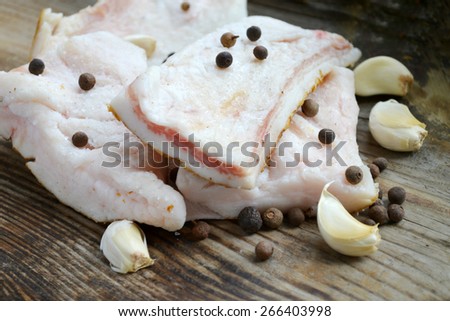 White pork fat called salo with garlic and pepper on wooden kitchen table