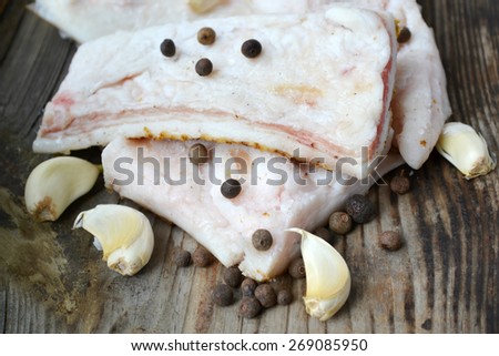 White pork fat called salo with garlic and pepper on wooden kitchen table
