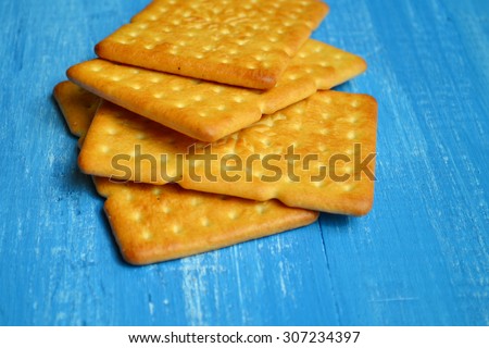 Tasty salty crackers on blue wooden background