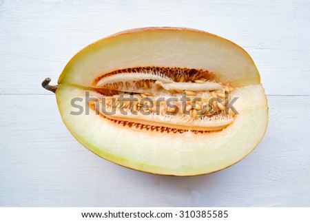 Tasty orange melon cut in half on white wooden board