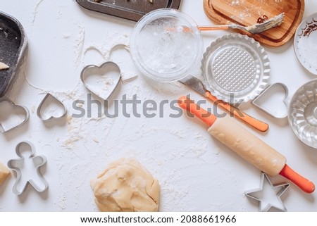 Background cooking wallpaper. On a white table covered with flour are baking tools and kitchen equipment. A set of cookie cutters for different types of cookies. Open space in the center for text. Foto stock © 