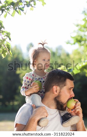 Father and toddler have fun with apple in garden
