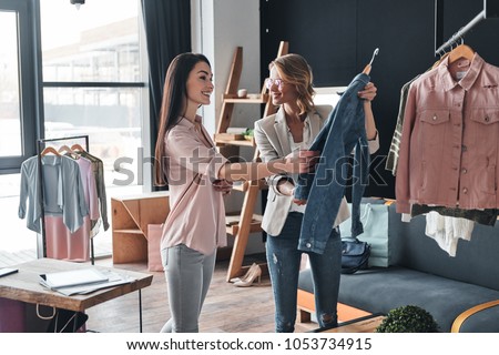 What do you think about this one? Beautiful young woman helping to choose clothes to her customer while working in the fashion boutique 商業照片 © 