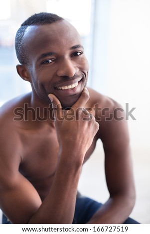 Shirtless black man. Shirtless African man holding hand on chin and smiling at camera