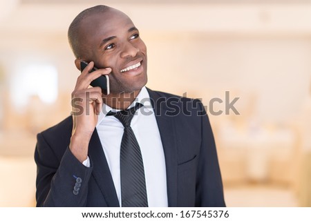 Businessman on the phone. Cheerful young African man in formalwear talking  on the mobile phone and smiling