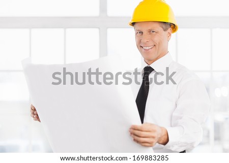 I have a plan. Confident senior man in formalwear and hardhat holding a blueprint and smiling at camera