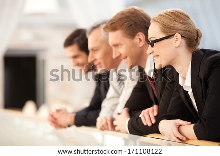Business team. Side view of four confident business people standing close to each other and looking away
