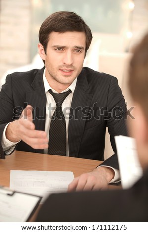 Business conversation. Two business people in formalwear discussing something while sitting at the table