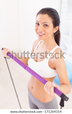 Working out is fun. Top view of cheerful young woman exercising in sport club