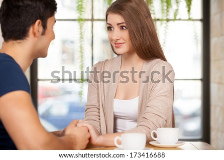 True feelings. Beautiful young couple sitting together at the restaurant and holding hands
