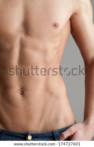 No fat! Cropped image of muscular man standing isolated on grey background