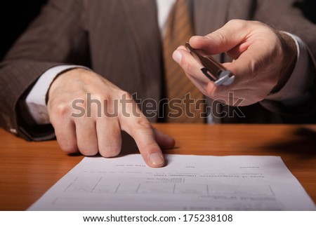 Your signature here! Cropped image of man in formalwear giving a pen to you and pointing a document while isolated on black background
