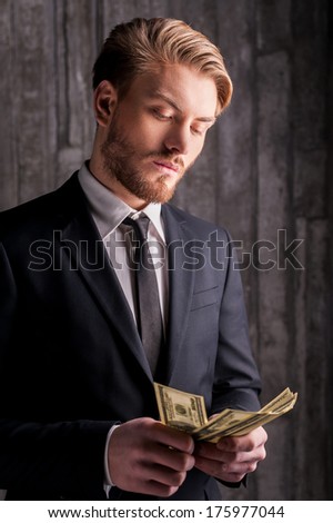 Wealthy handsome. Handsome young man in formalwear counting money