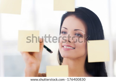 Writing new Ideas. Young  beautiful woman writing new ideas on adhesive notes