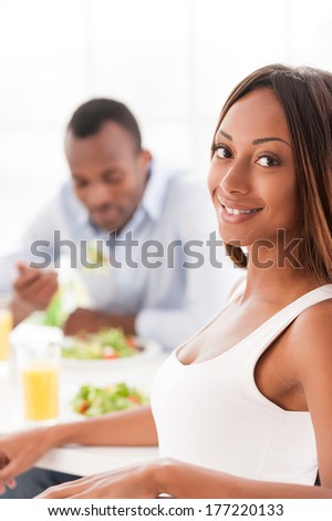 Having a healthy breakfast. Beautiful young African couple sitting together at the table and holding wineglasses