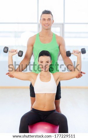 Young couple exercising at the fitness gym. Woman in gym with personal fitness trainer exercising