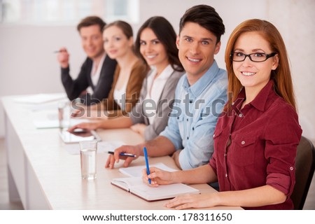 People working together. Group of young people sitting together at the table and smiling at camera