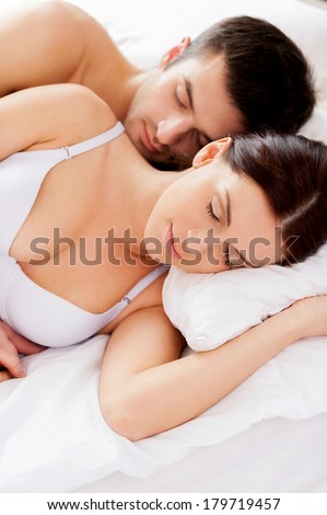 Sweet dreams. Top view of beautiful young loving couple sleeping together in bed