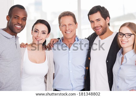 We are strong creative team! Group of cheerful business people in casual wear standing close to each other and looking at camera