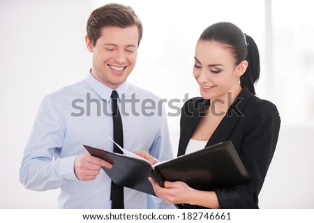 Discussing contract. Young man and woman in formalwear discussing something while holding folder with documents