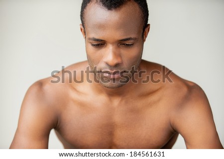 Man day dreaming. Handsome young muscular man looking down while standing against grey background