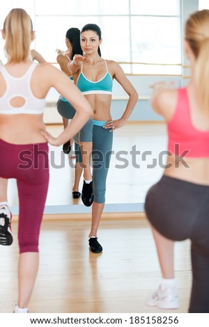 Aerobics class. Three beautiful young women in sports clothing exercising together and smiling