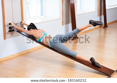 Woman stretching. Side view of beautiful young woman in sports clothing doing stretching exercises