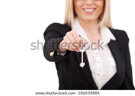 Here is your key! Cropped image of mature businesswoman stretching out key and smiling while standing isolated on white