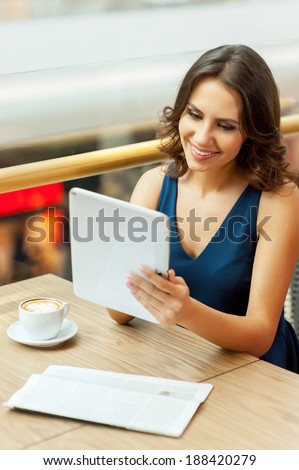 Coffee break. A beautiful young woman taking a break while working with digital tablet in restaurant