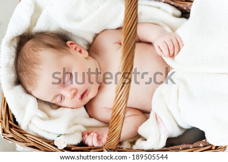 Sleeping in a basket. Top view of little baby sleeping while lying in wicker basket and covered with towel