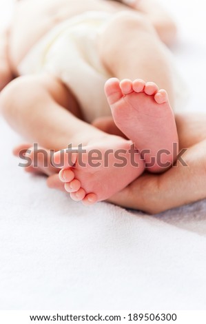 Tiny little feet. Close-up of father holding a tiny hand of his little baby