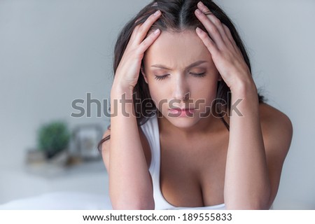 Depressed women. Young depressed women sitting in bed with her hand on face